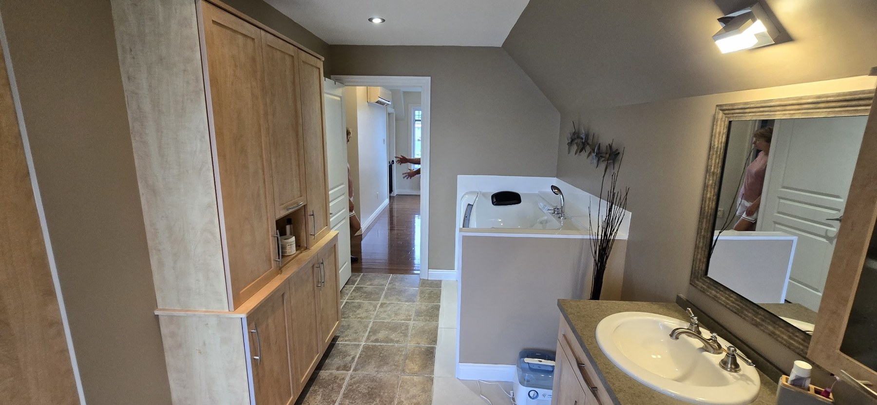 Salle de bain avec bain podium, armoires en bois, vanité et plancher en céramique